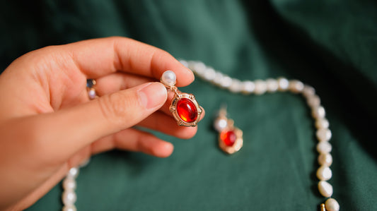 Goldene Ohrringe mit rotem Akzent und Perle